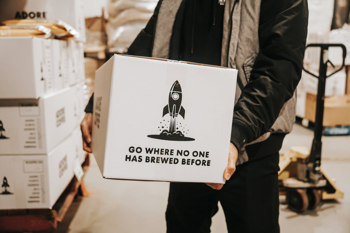 An Adore box with the rocket logo and the line Go where no one has brewed before